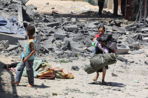 Palestinian children in Gaza walk through rubbles of buildings