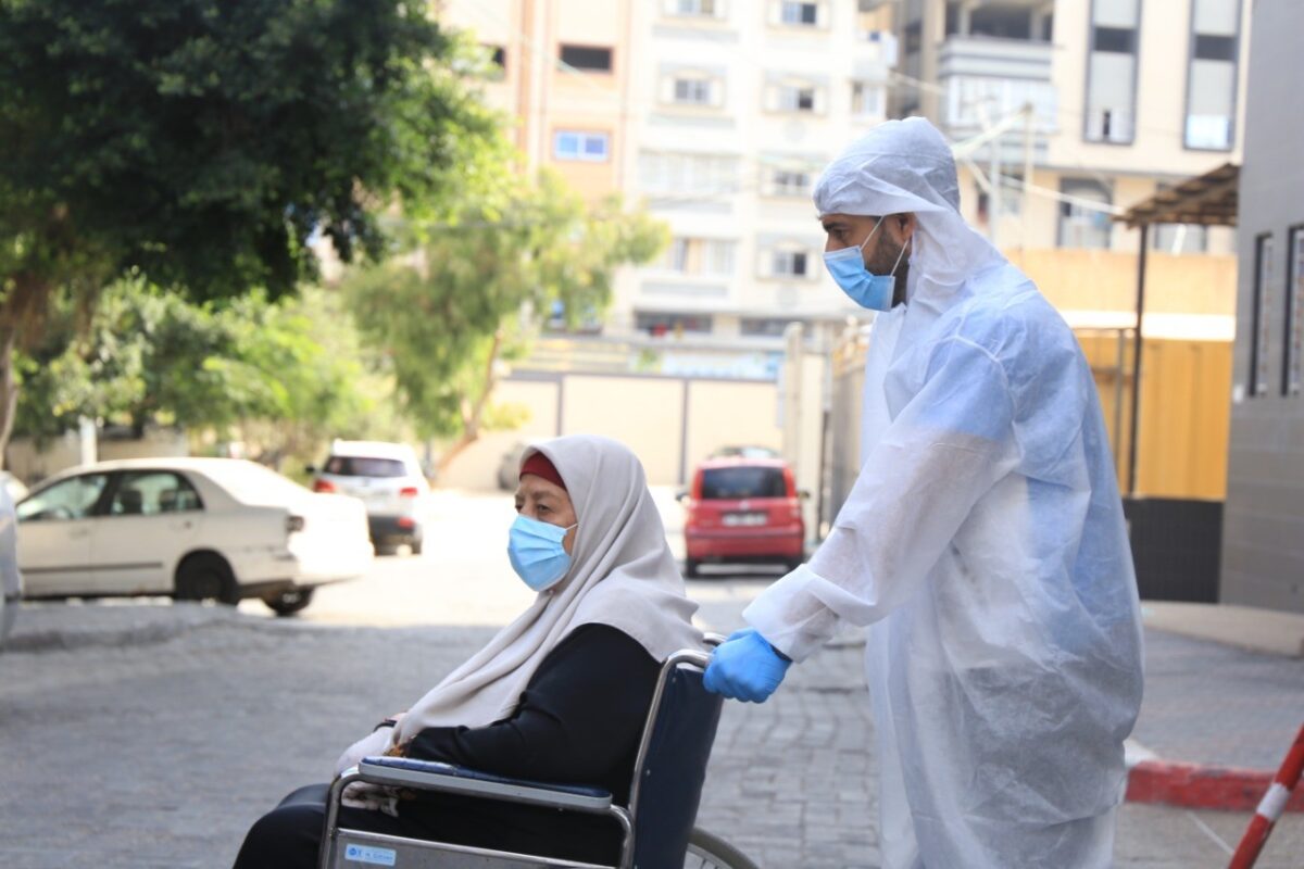 A healthcare worker in Gaza seen helping a Palestinian lady on a wheelchair